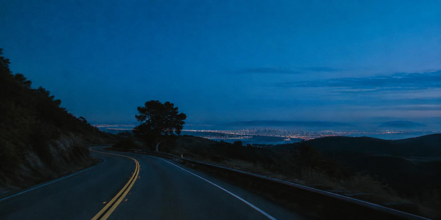 A quiet road winding through Bay Area hills at blue hour